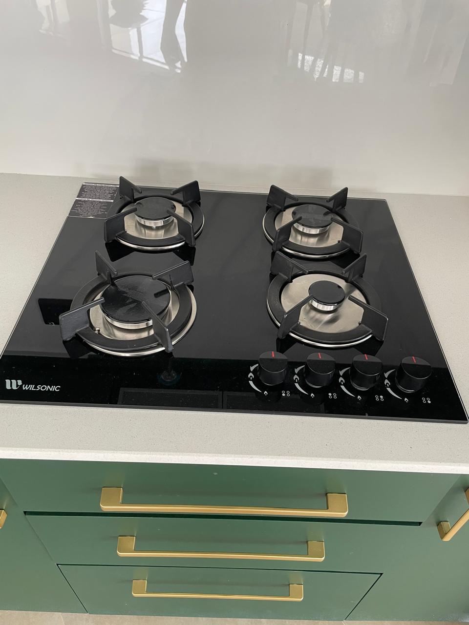 Four-burner Wilsonic black glass gas hob set into a stone worktop
