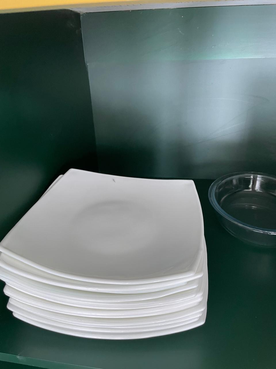 White square dinner plates provided in the kitchen cupboard