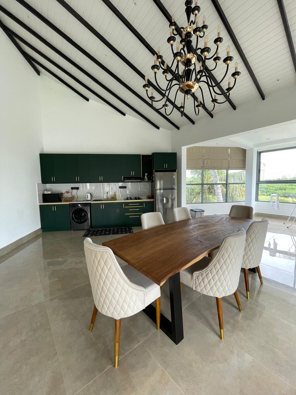 Live-edge hardwood dining table with cream quilted chairs beneath a chandelier